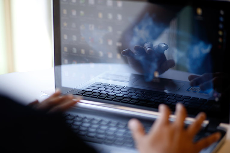 A close-up of a student's hands as they browse their laptop